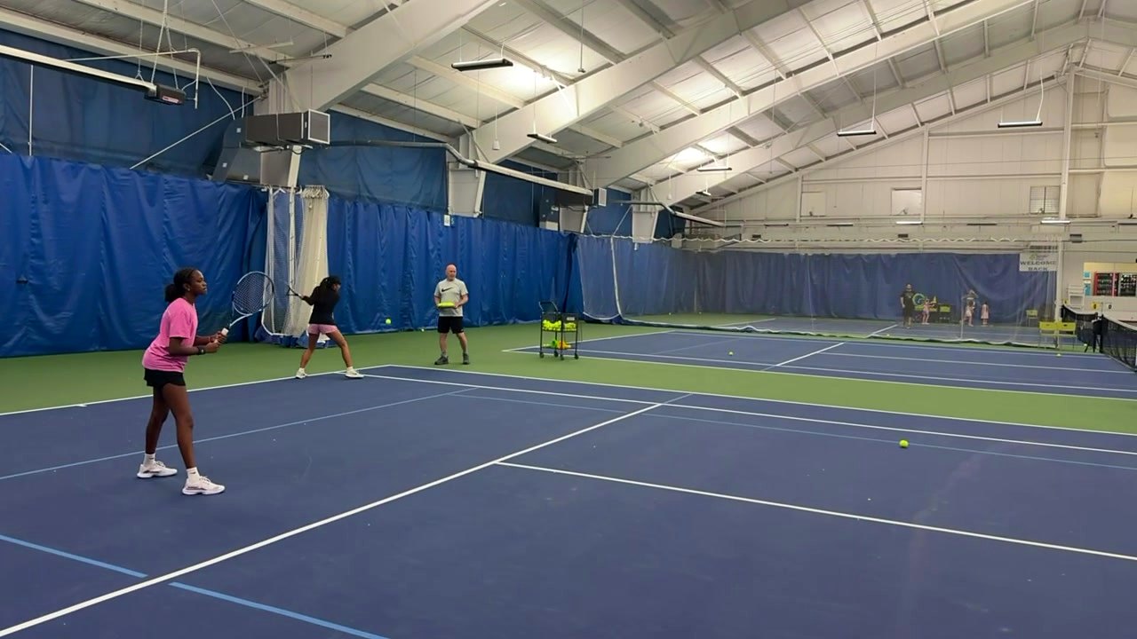 A junior player hitting a forehand during practice on the indoor courts