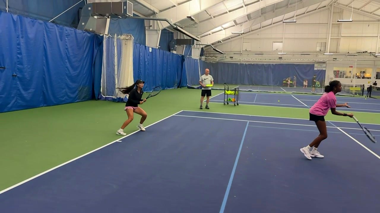 Junior players rallying during a training session on the indoor courts